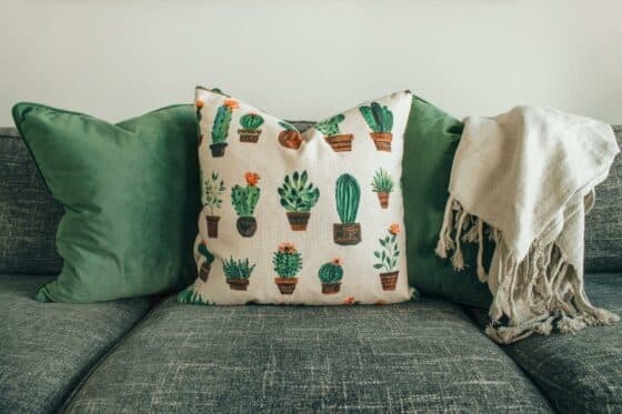 Image d'un canapé en tissu ave des coussins verts posés dessus.