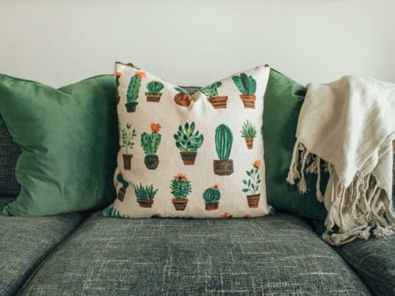 Image d'un canapé en tissu ave des coussins verts posés dessus.