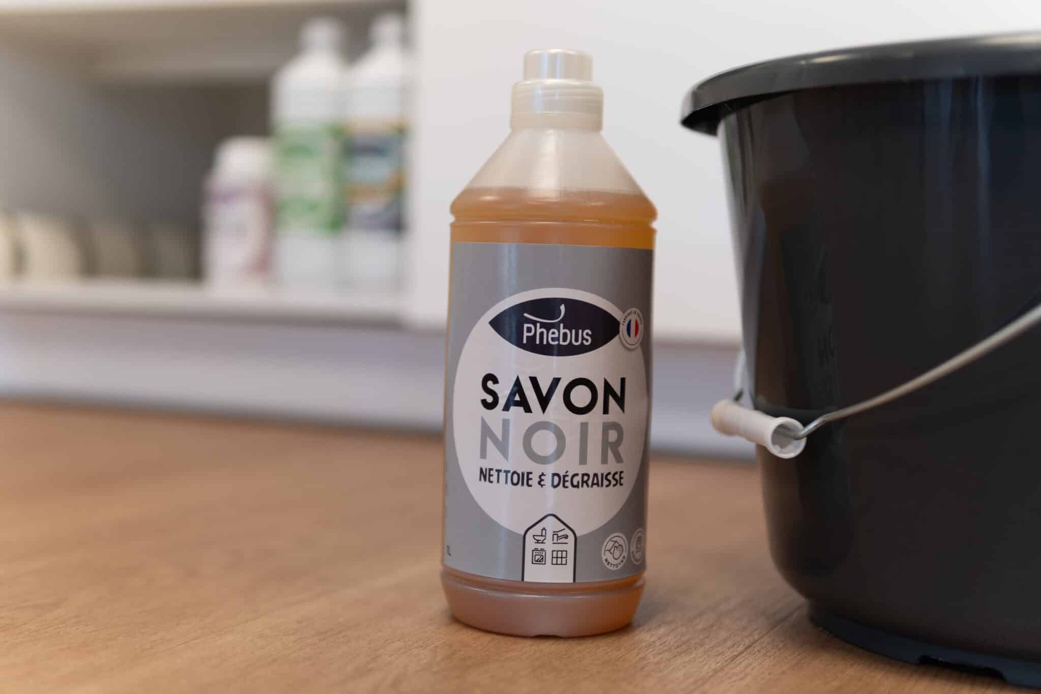 Photo de la bouteille de savon noir 1L Phebus posé sur le sol, à côté d'un seau