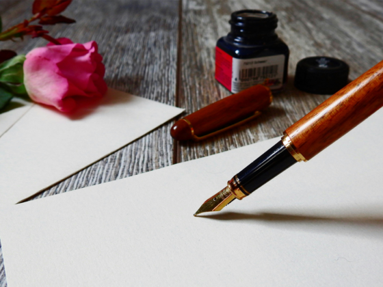 Pot d'encre posé sur un bureau avec un stylo plume